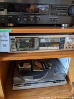 Top shelf cassette deck, middle TEAC tuner/cassette deck and bottom turntable inside oak cabinet
