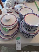 Overview of stacked plates, bowls, mugs, covered dishes and salt & pepper shakers on table