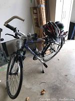 Full view of bike from front left showing frame, front wheel and handlebars with helmet perched.