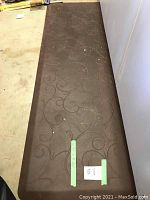 Full view of brown wellness mat with swirl pattern showing size and condition including dirt spots and some debris.