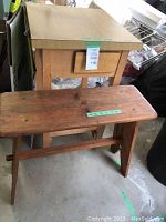 Wooden island with drawer drawer front, slatted shelf on bottom on wheels, and handmade wooden bench with flat seat in front of island
