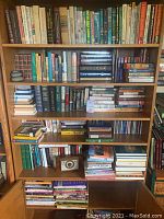 Bookshelf filled with various books on top four shelves, board games, CDs, and a roulette game on bottom shelves.
