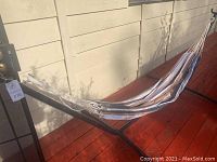 Full view of hammock installed on black metal frame stand on outdoor red deck