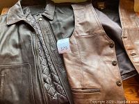 Wilsons chocolate leather vest and Cherokee dark chocolate leather bomber jacket laid flat, showing front closure and pockets