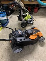 Cordless electric lawn mower in foreground and Ryobi electric pressure washer in background