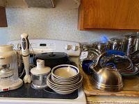 Wide view of stovetop with espresso machine, hand mixer, ceramic bowls, canisters, tea kettle, and other kitchenware items