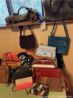 Overview of purses, wallets, and bags in a variety of colors and materials, stacked together.