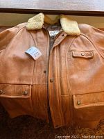 Full front view showing leather texture, button snap pockets, and wool collar.