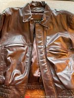 Front view of oxblood leather jacket showing collar, front zipped pockets with flaps, and elastic waistband.