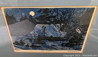 Framed numbered print showing a snow-covered cabin at night, signed and numbered by Allen Smutylo.