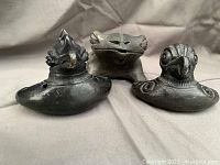 Front view of black pottery bird ocarina flutes and frog/toad figurine