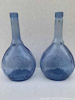 Front view of two blue glass Jenny Lind bottles showing their shape and embossing.