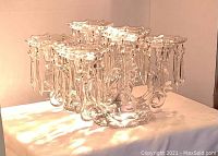 Pair of clear glass candelabras with multiple candle holders each adorned with hanging crystal drops.