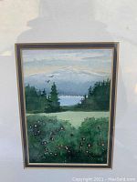 Framed original watercolour painting showing landscape with mountains, trees, lake, and flowering bushes under glass.