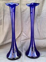 Pair of tall cobalt blue glass bud vases photographed front side with beige fabric background
