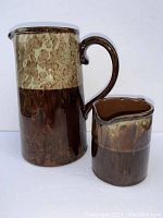 Two vintage pottery pitchers, larger one Webster with sponge decoration, smaller one Lingard, both brown and beige glazed.