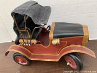 Side view of the model car showing wooden body, fabric canopy, and attached front wheels.