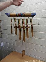 Front image of bamboo wind chime showing seven hanging bamboo tubes and colorful painted top frame.