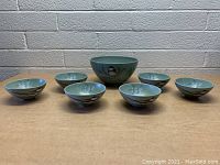 Set of one large serving bowl and six small bowls showing Winterwood pattern with birds and pine branches