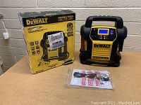 DeWalt jump starter device with original box and manual on table, side view