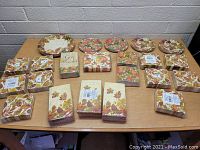 Top view of the lot containing multiple stacks of paper napkins and several disposable plates with Thanksgiving and autumn leaf patterns.
