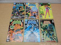 Front view of six Batman and Batman and the Outsiders comics laid flat on a table, showing colorful covers from 1985-1986.