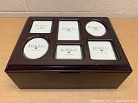 Front view of wooden keepsake box with six photo slots on the lid showing Bombay brand paper inserts