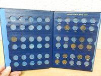 Blue coin collector book opened to show slots for Indian Cents from 1882-1909 with 12 Indian Head pennies inserted in various dated positions.
