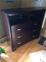 Front view of the wooden chest showing three drawers with silver handles and a top open shelf section.