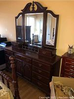 Full view of wooden dresser with tri-fold mirror on top, showcasing layout and design.