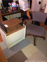 Office chair next to file cabinet and shelf in a room with carpeted floor.