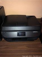 Front angled view of black HP OfficeJet 4650 all-in-one printer showing top lid, touch screen, and output tray.