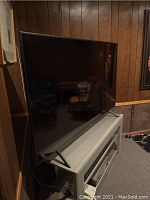 Front three-quarter view of TV on stand showing screen and bezel