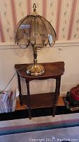 Wood demilune side table with lamp on top showing full side view
