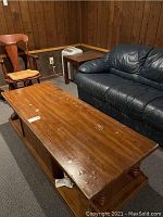 Photo of wooden coffee table with visible finish buckling and surface damage in a basement setting