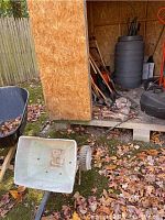 Photo of shed exterior with various yard tools stored inside and black barrel visible