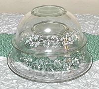 Stacked view of both Pyrex mixing bowls showing clear glass and white floral Colonial Mist pattern.