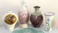 Four vintage large studio pottery vases with varied colors and shapes on a tabletop, showing the lot contents.
