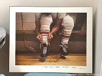 Full view of the signed print showing a man tying hockey skates with signatures and inscriptions on the white margin.