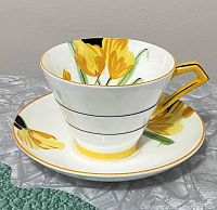 Teacup and saucer set showing yellow crocus floral pattern with gold accents and geometric handle, front view