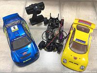 Overview shot showing RC chassis, blue Subaru body, yellow Duratrax body and black transmitter