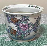 Front angle view of the planter showing colorful flowers and detailed floral pattern in purple, orange, and green tones.