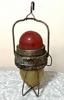 Vintage dual emergency vehicle safety light, showing the red dome top and white dome bottom inside the rusted chrome cage with hanging hook.