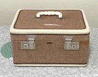 Front angle showing the fabric texture, white handle, cream trim, and metal double locking latches.