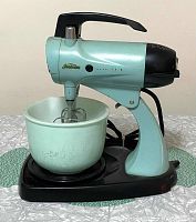 Side view of vintage Sunbeam Mixmaster Model 12 in turquoise with mixing bowl on black base and two beaters attached.