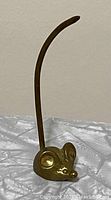 Side angle of vintage brass mouse ring holder showing head and curved tail