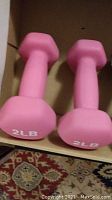 Close-up photo of pair of pink 2 lb neoprene dumbbells showing shape and marking