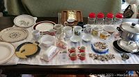 Full collection spread on table including mugs, platters, jars, cookware, porcelain rabbits, butter dish, wooden platter, and sea shells.