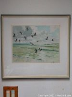 Framed seascape etching with seagulls flying over ocean waves under cloudy sky.