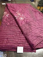 Folded view of the purple quilted bedspread with visible embroidery
